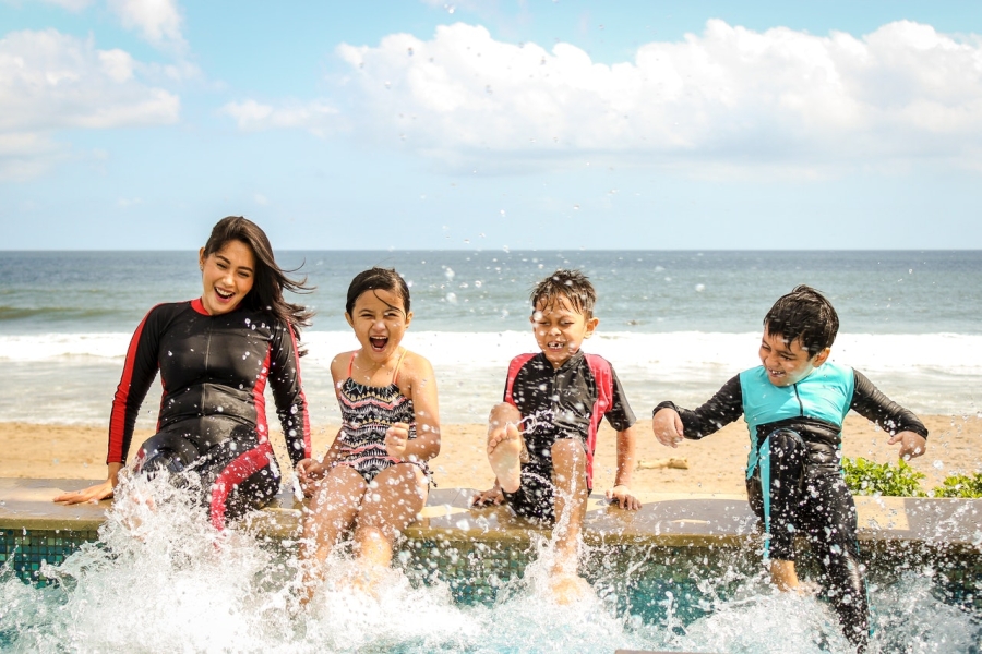 A woman and three children playing with water at a beach